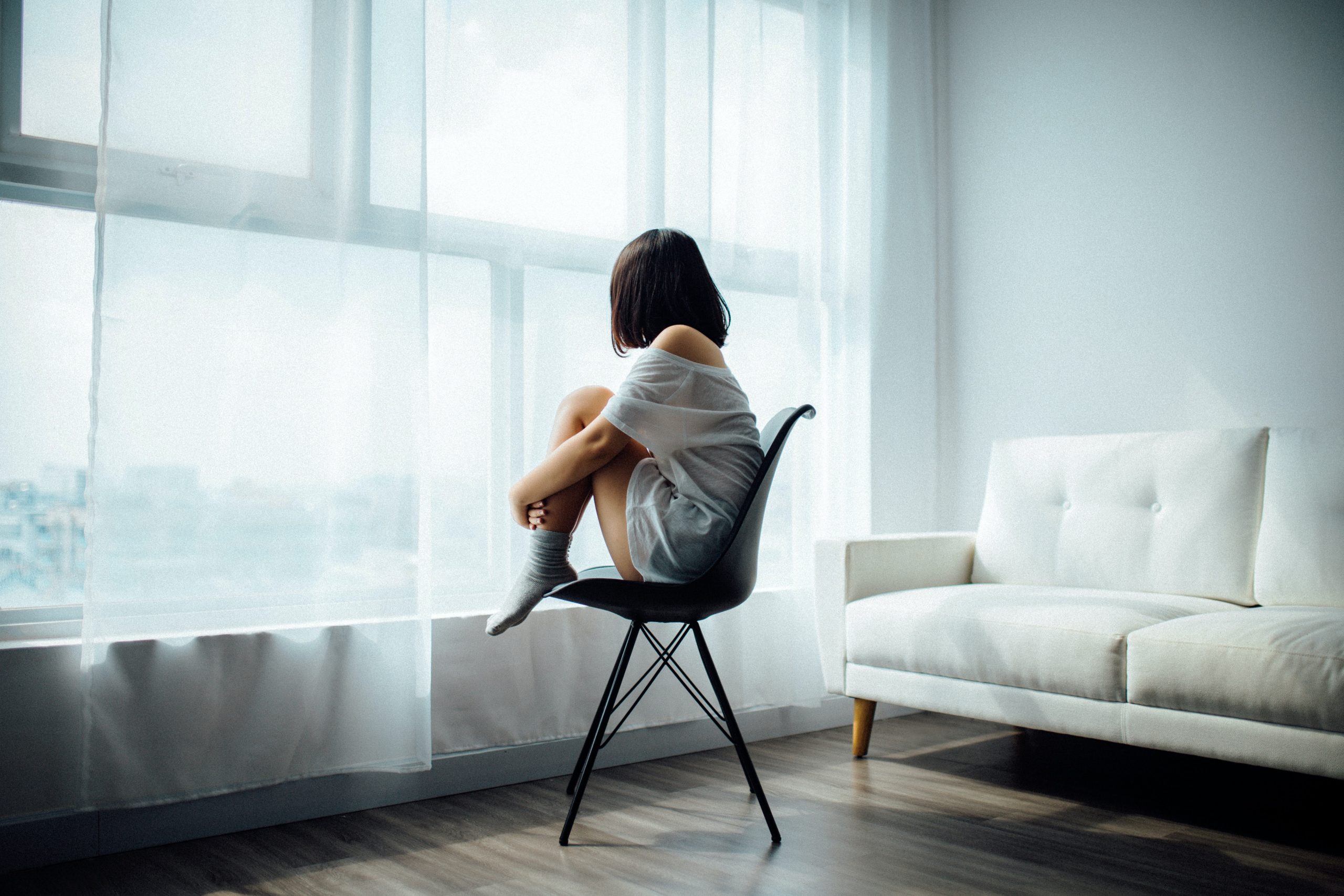 A woman sitting in a chair staring out of a large window
